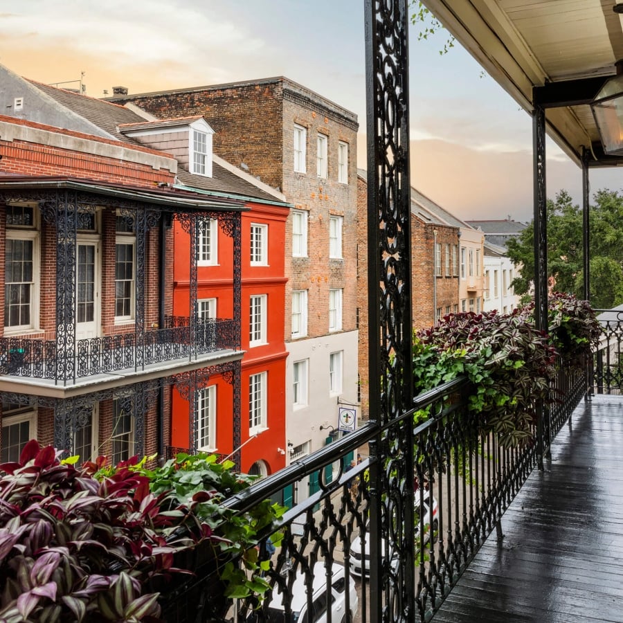 View from Bienville House hotel balcony with dark wood, looking across the street at colorful French Quarter buildings.