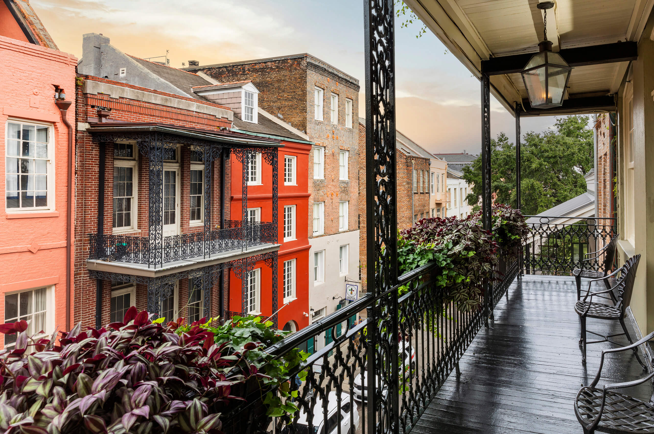 View from Bienville House hotel balcony with dark wood, looking across the street at colorful French Quarter buildings.