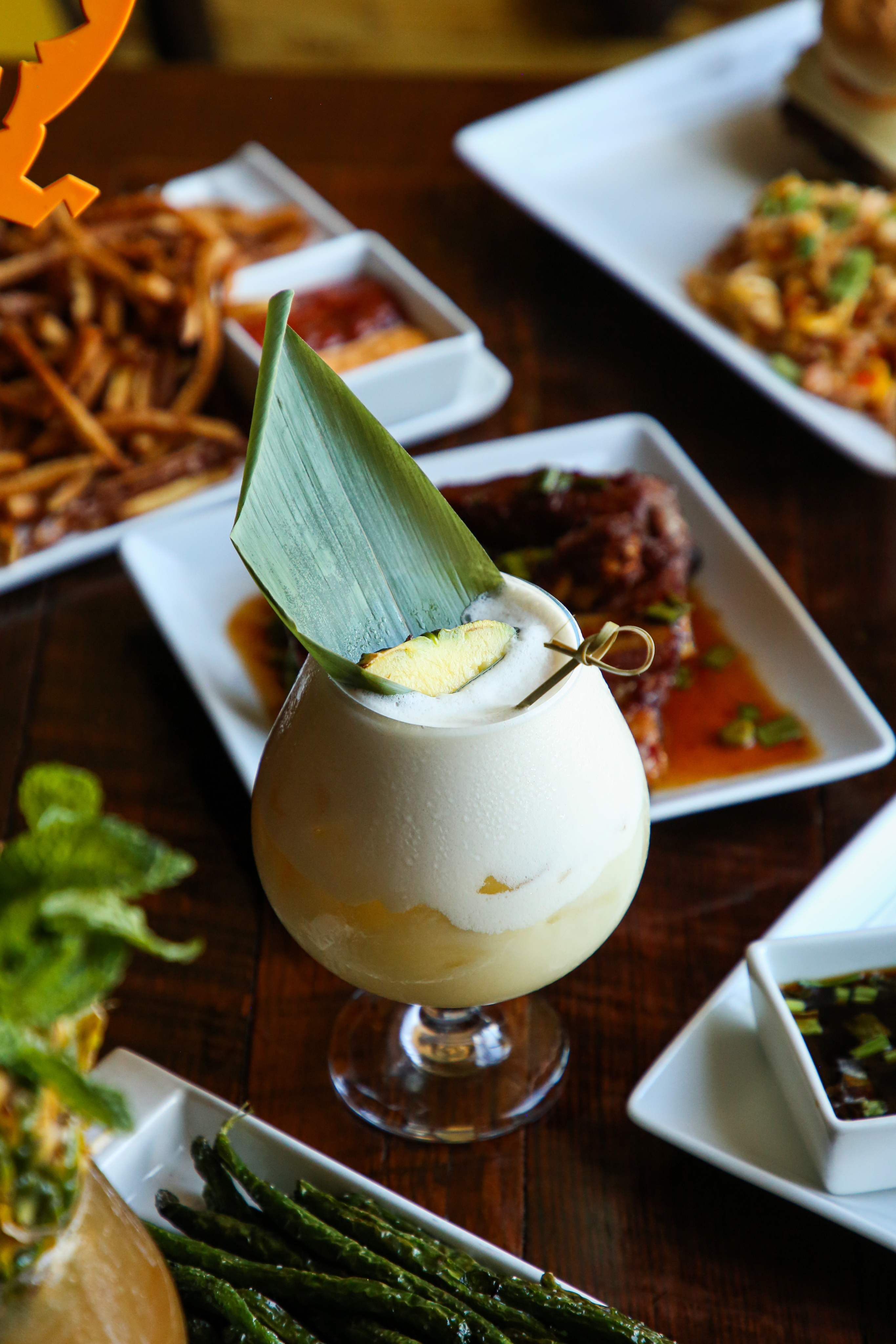 a creamy cocktail with a leaf and lime wedge garnish