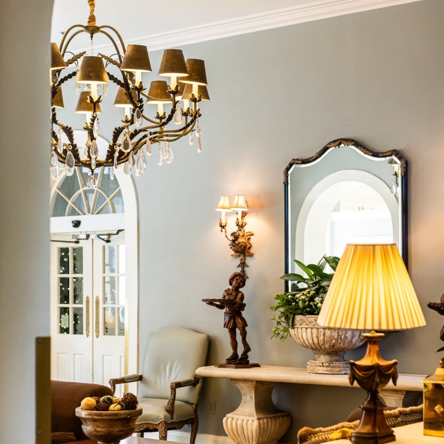 A view of the hotel lobby decorated with a golden chandelier, a scalloped mirror, and classic-style furniture.