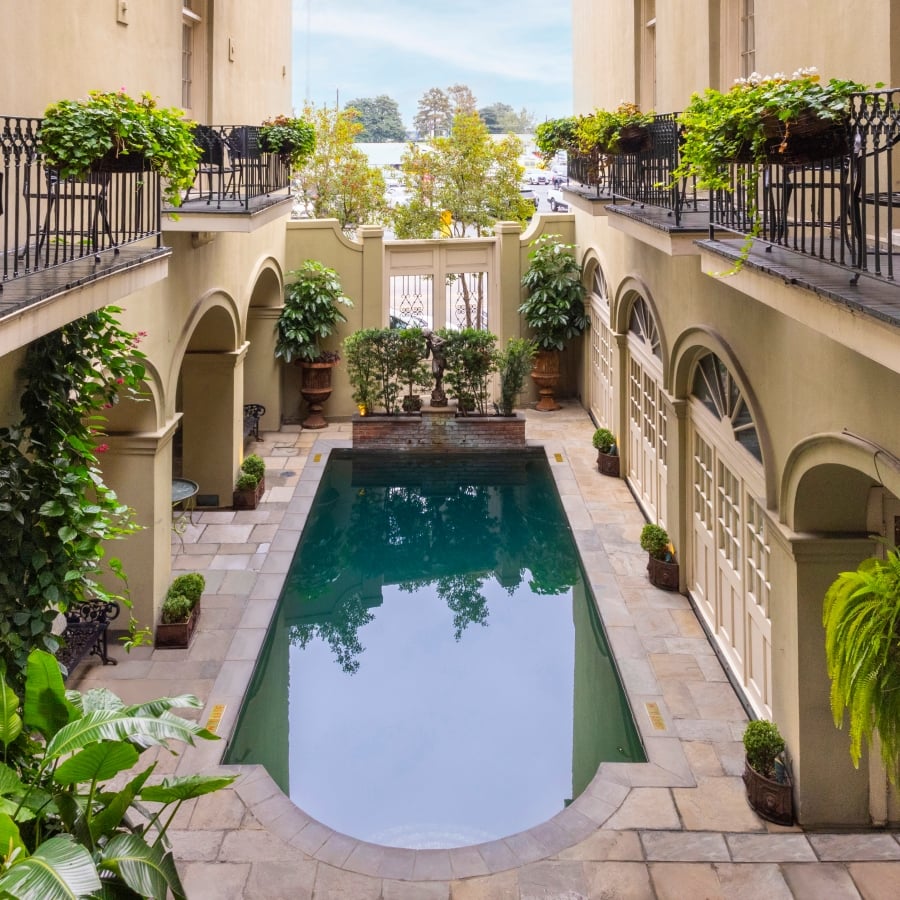 An overhead view of the Bienville House courtyard pool, surrounded by arched doorways, balconies, and plants.