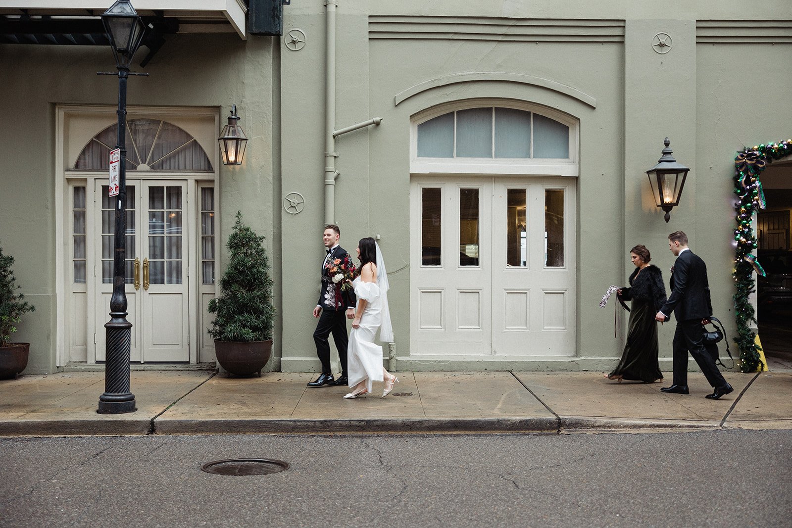 The bride and groom walk hand-in-hand down a city sidewalk after their wedding ceremony.