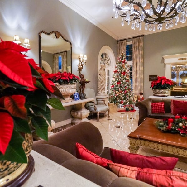 The Bienville House hotel lobby decorated for Christmas, featuring red poinsettias, velvet sofas, and a lighted Christmas tree.