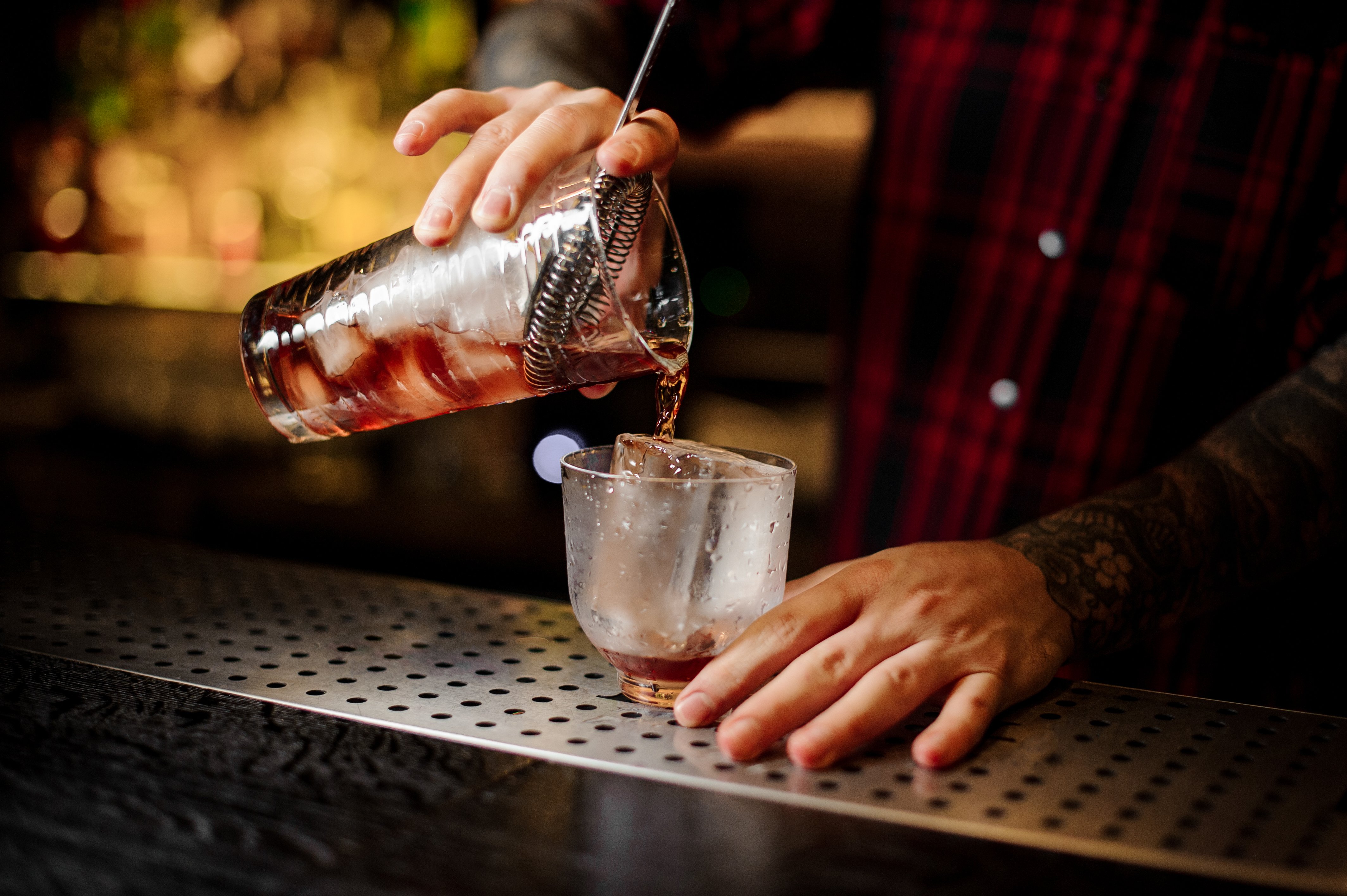 A bartender pouring a drink into a glass.
