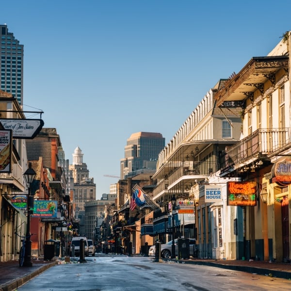 A long, street-level view down a New Orleans street lined with historic buildings and distant skyscrapers.