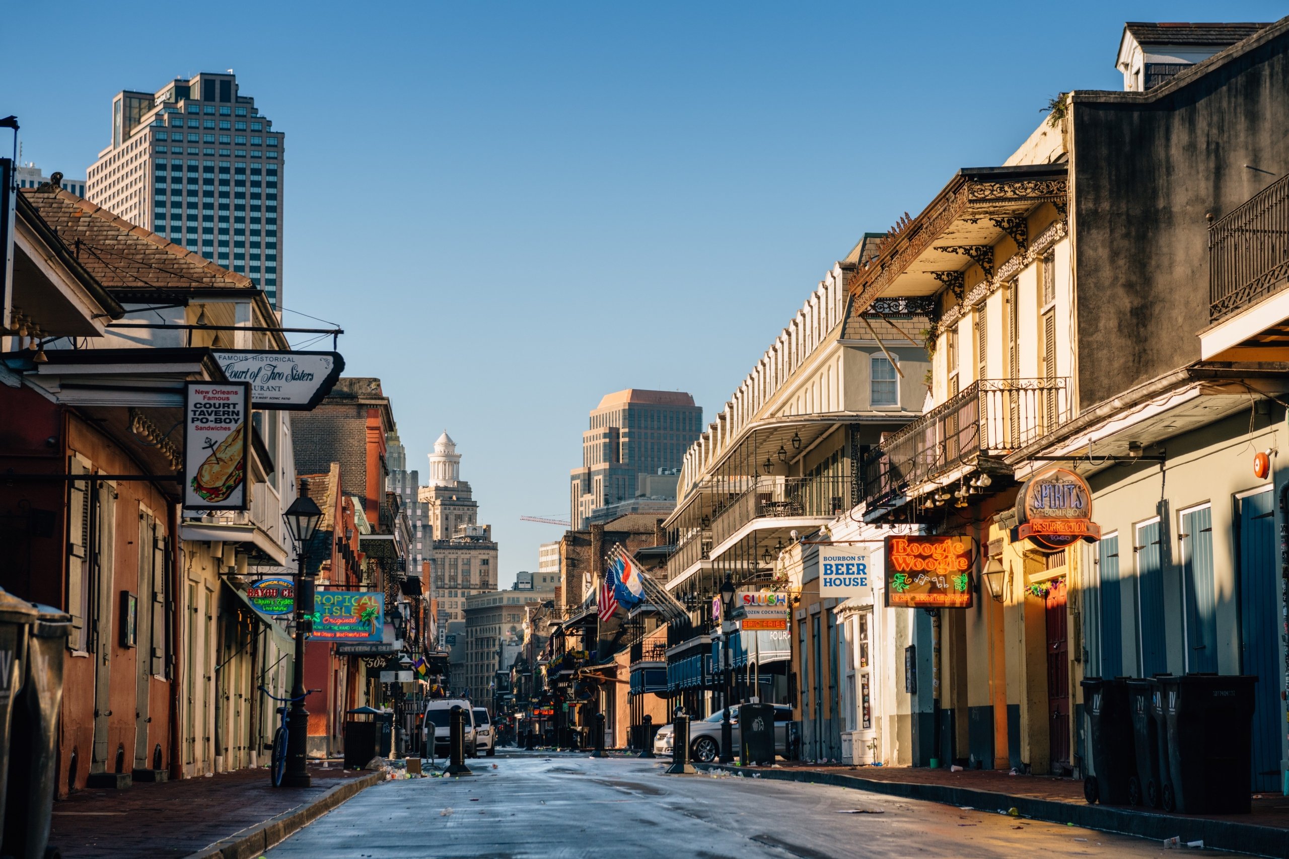 A long, street-level view down a New Orleans street lined with historic buildings and distant skyscrapers.