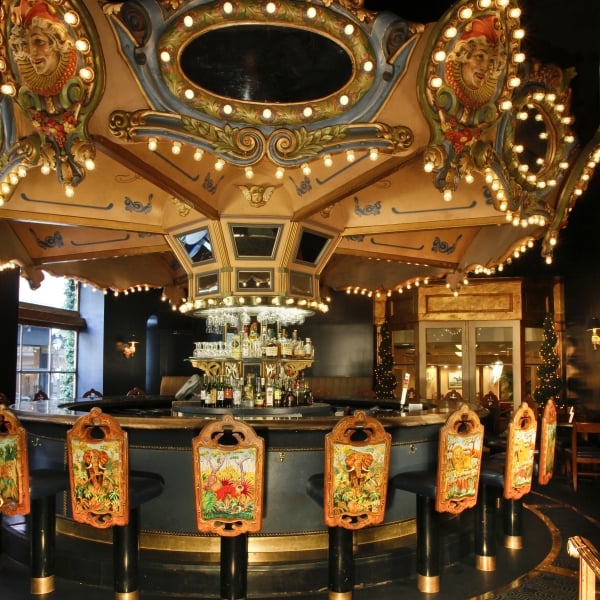 The Carousel Bar interior, featuring a revolving circular bar with ornate, vintage carousel decorations and painted barstools.