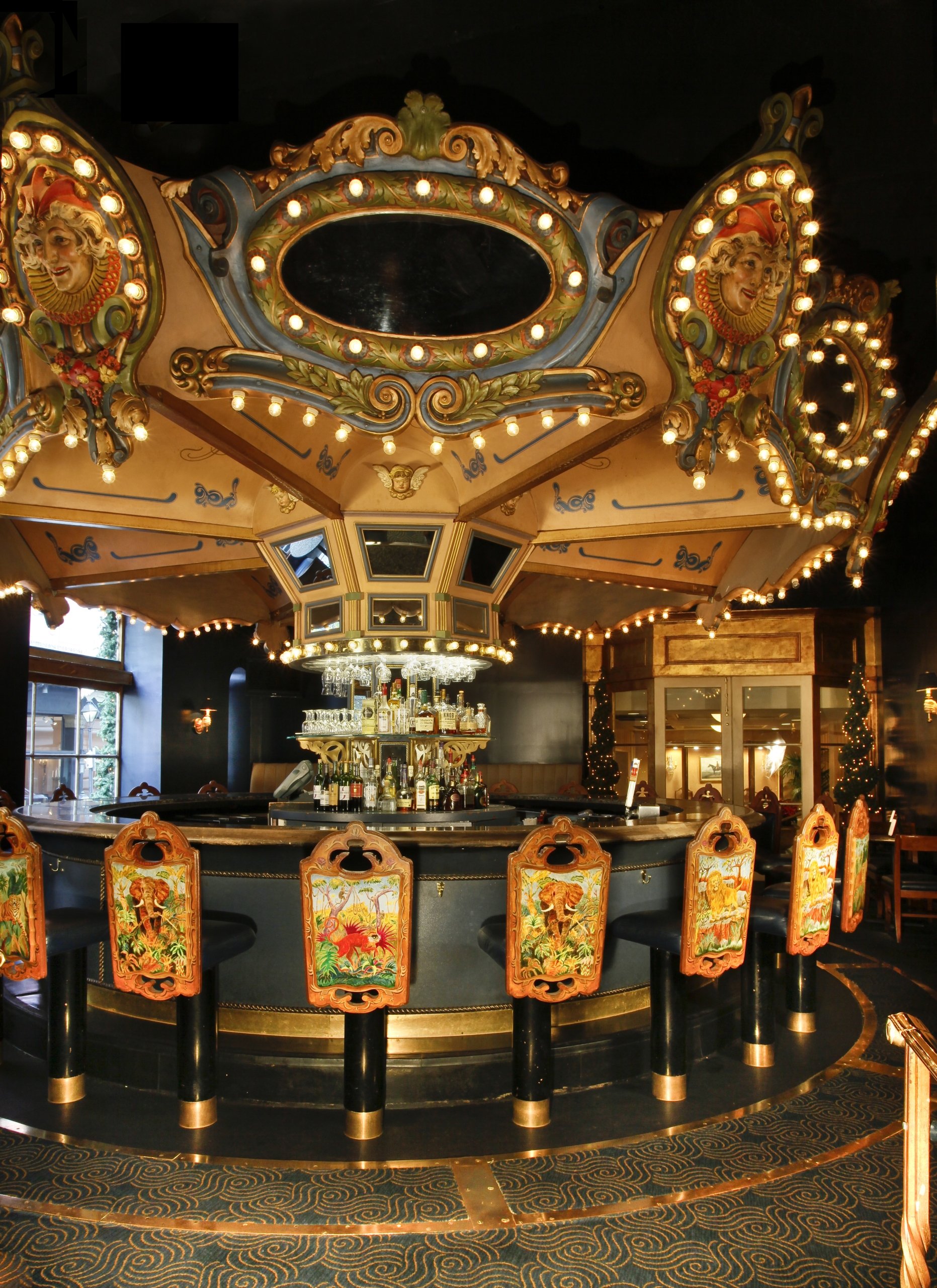 The Carousel Bar interior, featuring a revolving circular bar with ornate, vintage carousel decorations and painted barstools.
