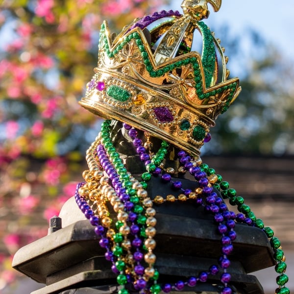 Outdoor Mardi Gras Crown and beads on light post in sunshine