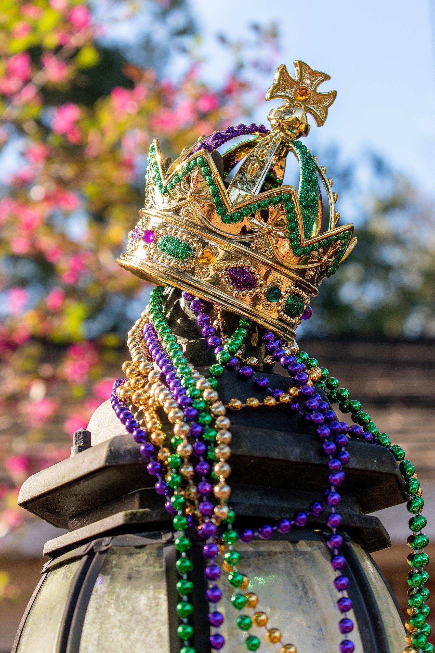 Outdoor Mardi Gras Crown and beads on light post in sunshine